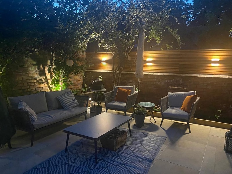 Dining set on patio with Harvest sawn sandstone garden edging stones along edge of narrow border against wall. 