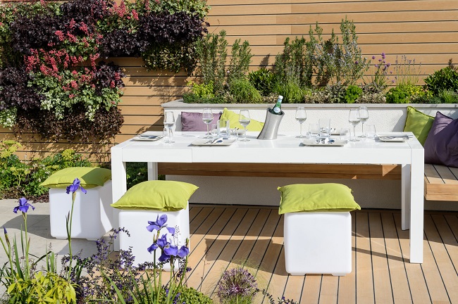 White table with 2 square stools on teak-coloured  decking in Sociability, Best Lifestyle Garden, BBC GW Live 2015