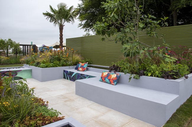 Egyptian Beige Limestone paving with grey raised beds, slatted fence and low leafy planting by Emma Tipping.