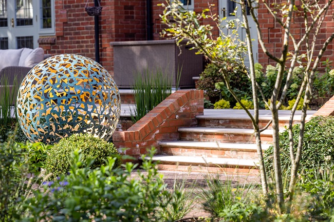 Egyptian Beige sawn limestone step treads rise between brick flank walls to matching paved area with raised decking in background.