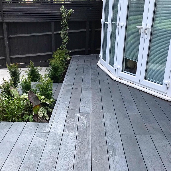 Small decking area in Millboard Brushed Basalt Enhanced Grain outside curved french doors.