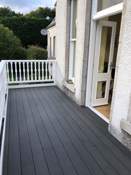 French doors open onto rectangular balcony with white railings, decked with Dark Ash Brushed composite decking