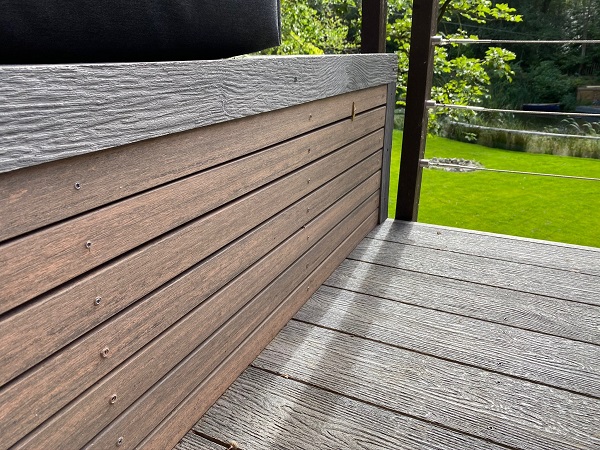 Close view of bench faced with Chestnut composite battens on light grey decking. 