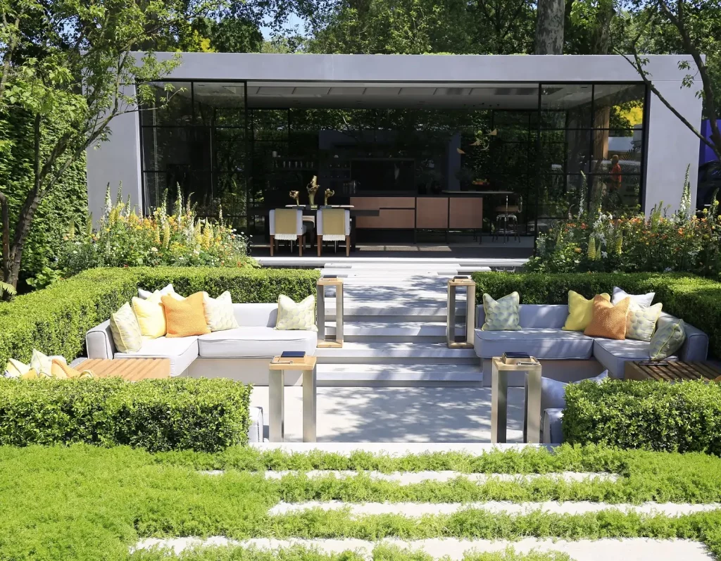 Jura Grey plank paving runs to sunken seating area with steps on other side towards open-fronted studio in LG Eco-City Garden.