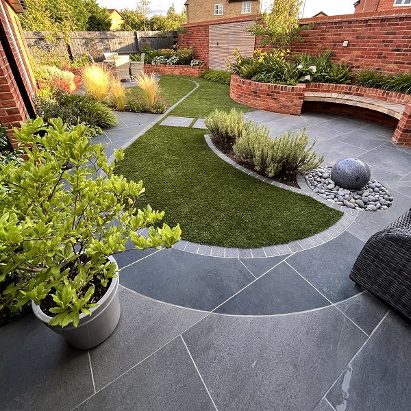 Charcoal and Platinum Grey porcelain paving curves round teardrop-shaped grass in walled garden