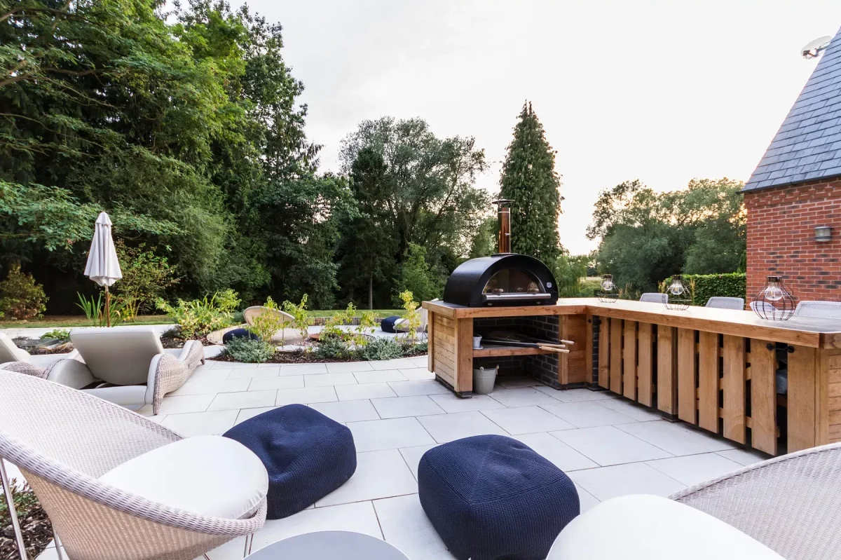 2 blue pouffes on large patio of Sandy White 600x600 porcelain slabs with dining bar and barbecue.