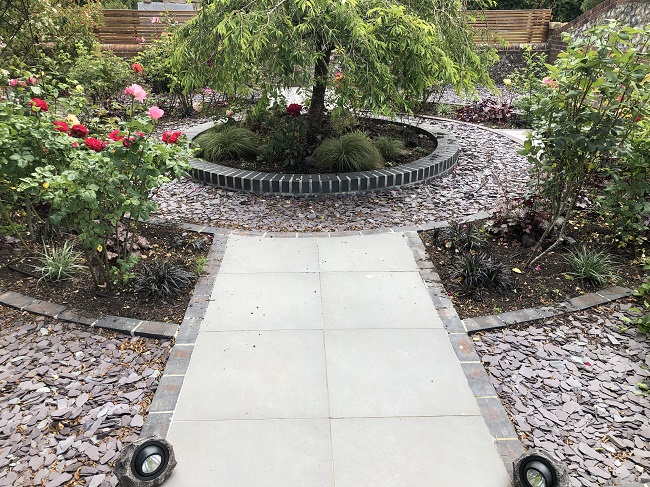 Wide path 2 Steel Grey porcelain 600x600 patio slabs wide tapers slightly to round paving feature with tree in circular bed in centre.