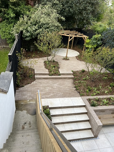 View down onto garden paved with Stone Grey clay pavers, with Florence White porcelain steps and paving circle.