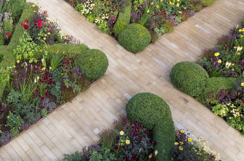 2 paths cross, dividing 4 beds with topiary and low hedges creating planting triangles