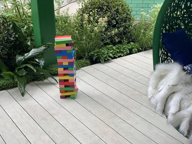 DesignBoard composite decking with multi-coloured tower of bricks by pillar and planted border. 